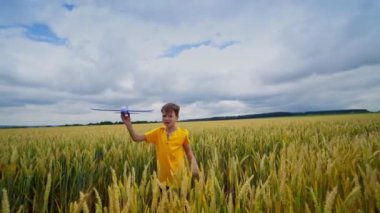 Mutlu çocuk dışarıda oynuyor. Sevimli çocuk oyuncak oyunu oynuyor ve sevinçle arkasını dönüyor. Sarı sahadaki çocuk tek başına oynuyor..
