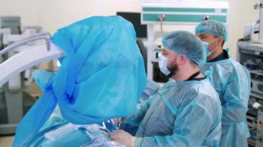 Doktorlar bir ameliyat yapar. Mavi koruyucu üniformalı tıp çalışanları klinikteki ameliyathanede çalışıyor. Ameliyathanede cerrahi prosedür.