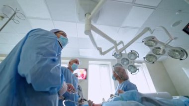Ameliyathanede bir grup doktor var. Uzmanlar bir ameliyat yapar. Cerrahlar arka planda modern tıbbi aletler kullanırlar. Aşağıdan görüntüle.
