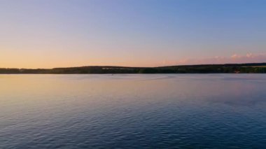 Gün batımında nehir. Akşamları sakin suyun üzerinden uçuyorum. Berrak gökyüzünün altında sakin bir suyun inanılmaz manzarası. Doğada suda yüzen bir teknenin silüeti..