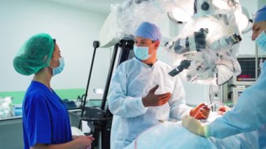 Klinikteki bir grup doktor. Tıp çalışanları modern hastanedeki ameliyat sırasında konuşuyorlar. Doktor ameliyathanede kadın uzmana danışıyor..