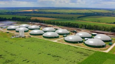 Tarlalardaki modern biyogaz fabrikası. Yazın güzel bir çevre arasında biyokütle üretimi için küçük bir çiftlik. Hava görünümü.