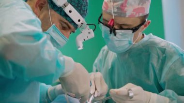 Profesyonel doktorlar ameliyat yapıyor. Kafasında tıbbi ışık olan cerrahların yüzleri ameliyat yapıyor. Yakın plan. Sağlık hizmetleri kavramı.