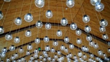 Cam ampullerin içi lükslü. Yuvarlak şekilli fütüristik kolye ışıkları. Tavanda bir sürü parlak top var..