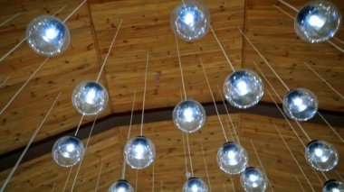 Bir sürü kristal küçük topları olan rahat bir tavan. Beyaz kablolarda asılı yuvarlak ampuller. Parlak lambaların modern tasarımı.