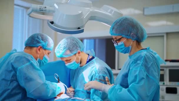 一组医生来照顾病人 在诊所手术室 身穿蓝色工作服 戴口罩的医护人员使用手术器械 — 图库视频影像