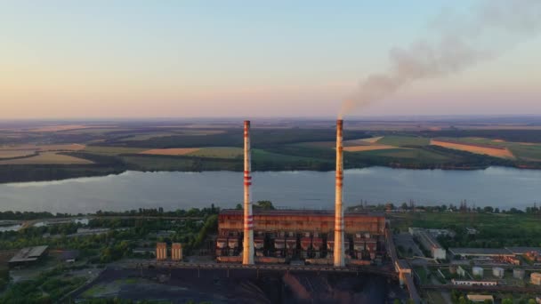 美しい自然の中にある化学プラント 日没時に川の近くで喫煙パイプを有する工場 パイプは有害な排出物を排出し 環境を汚染する エアリアルビュー — ストック動画