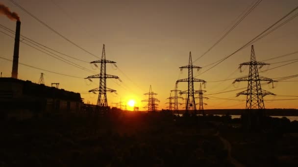 日没の産業地帯 工場近くの高圧電気線は 夕方に汚れた煙でパイプが付いています パワーステーションのダークシルエット — ストック動画