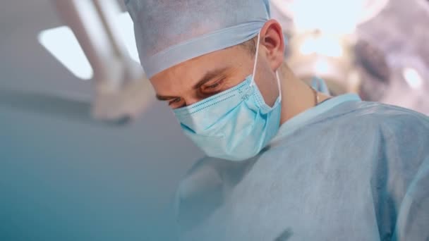 Mężczyzna Masce Portret Chirurga Mundurze Medycznym Patrzącego Dół Podczas Zabiegu — Wideo stockowe