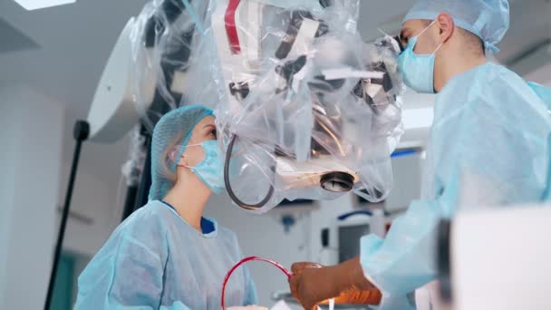 현미경을 신경외과 유니폼을 전문가들은 수술을 수행합니다 의사는 수술에서 현대적인 장비를 — 비디오