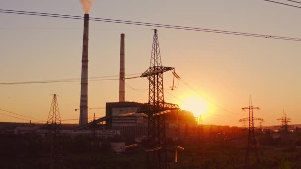 日落时的电塔 工业管道背景图上的高压电塔 工厂附近的输电线路 晚上向空气中排放脏烟 — 图库视频影像