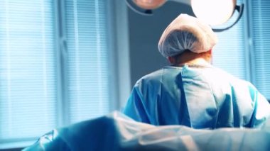 Ameliyat sırasında kadın doktor. Mavi üniformalı ve maskeli tıp uzmanı kadın hastanede cerrahi ekipmanlarla çalışıyor..