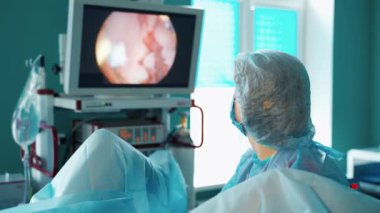 Doktor tıbbi monitöre bakar. Bir hastayı ameliyat eden ve hastanın organlarını ekranda gözlemleyen kadın üniformalı bir uzman. Modern tıp.