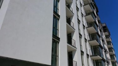 Yeni inşa edilmiş bir apartmanın ön cephesi. Camdan pencereleri ve balkonları olan modern bir bina. Konut mimarisi.