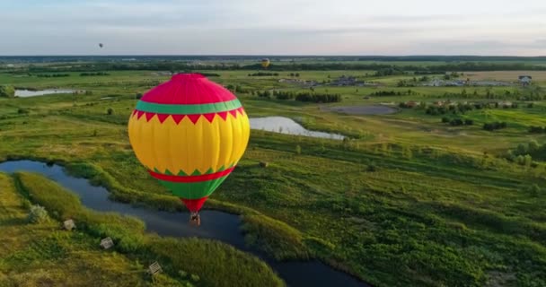日没時に空中を旅する 田舎を飛んでいる熱気球 フィールドと湖の上にカラフルな空気スタット 空からの眺め 周りのモーションカメラ — ストック動画