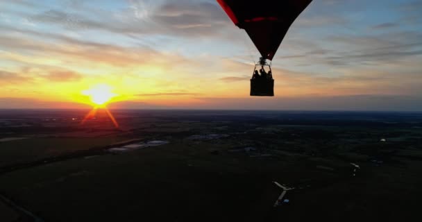 人々は熱い気球で旅行する オレンジ色の夕日に対して空を飛んでいるハートの形で美しい赤い空気スタット — ストック動画