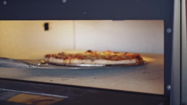 ピザはオーブンで準備をしています オーブンドアを開けてピザの準備をチェックするシェフ クックはピザリングを使用して準備のためのピザをチェック — ストック動画