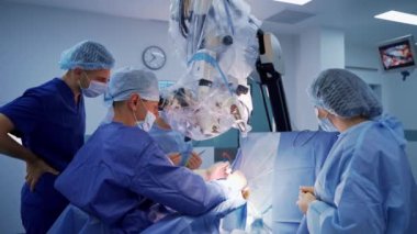 Profesyonel beyin cerrahı mikroskoptan bakar. Tıbbi ekipmanlar ameliyatta. Ameliyathanede üniformalı bir grup doktor var..
