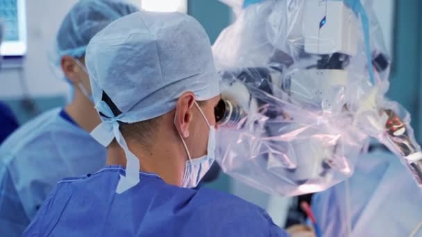 Cirujano Mira Microscopio Vista Posterior Cabeza Del Médico Durante Neurocirugía — Vídeo de stock