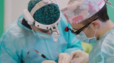 Klinikte cerrahların işi. Özel el fenerlerinde çalışan sağlık çalışanları hastanede cerrahi aletlerle operasyon yapıyorlar. Yakın plan..