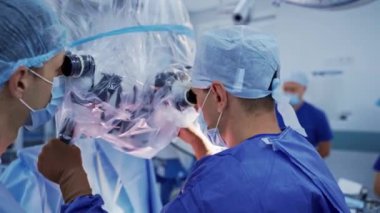 Cerrahlar modern tıbbi ekipmanlara bakarlar. Profesyonel doktorlar, hastanedeki ameliyattan önce mikroskobu özelleştirirler..
