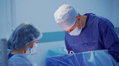 Doktor ve hemşire ameliyathanede. Profesyonel beyin cerrahı ve mavi üniformalı kadın asistan bir ameliyat gerçekleştirdiler..