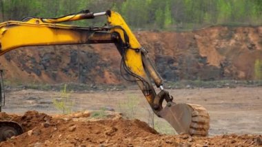 Büyük kazıcı kovası toprağı kepçeler. Büyük kürekli sarı metal kazı makinesi toprağı kazıyor. Yavaş çekim.