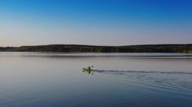 Nehirde kayak yaparken. Akşam sularında yüzen bir teknede. Günbatımında kürek çeken adam. Hareket eden kamera var. Hava görüntüsü. Boş doğa konsepti.