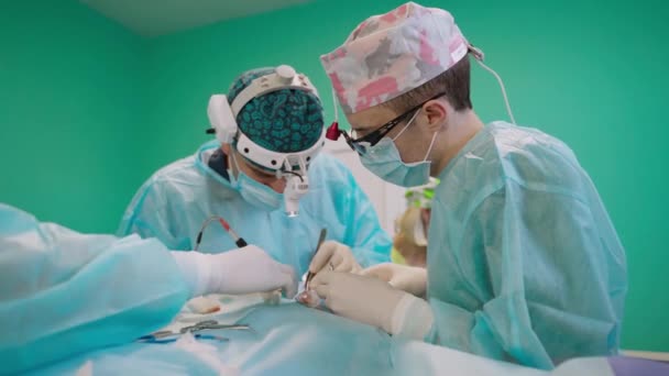 外科医生的团队合作 穿着医疗制服和外科口罩的专业医生用医疗仪器进行手术 护士给病人提供无菌手术器械 — 图库视频影像