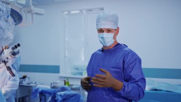 医生在手术室里对着摄像机讲话 身穿蓝色军服戴口罩的专业外科医生解释了外科手术中的重要事实 — 图库视频影像
