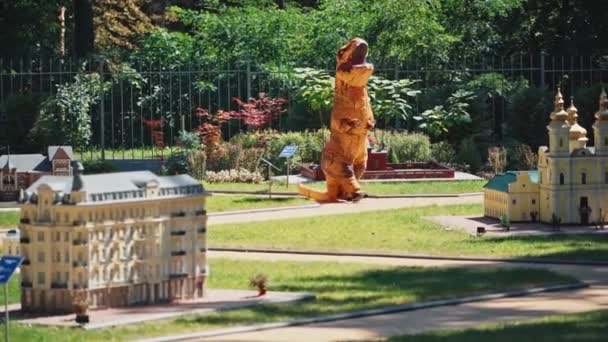 Zabawny Dino Mieście Zabawek Świeżym Powietrzu Osoba Dużym Pomarańczowym Kombinezonie — Wideo stockowe