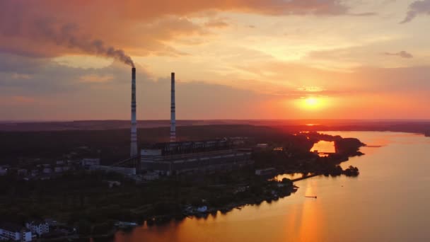 日没に川の近くにある工場 夜空に対するパイプを吸う工業用プラント 生態学的な問題 モーションカメラを取り戻した エアリアルビュー — ストック動画