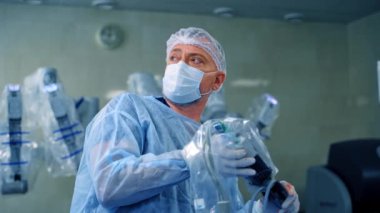 Doktor ameliyathanede. Cerrah modern ekipmanlarla bir ameliyat yapıyor. Robot kollu maskeli bir doktorun portresi. Tıpta yeni teknolojiler.