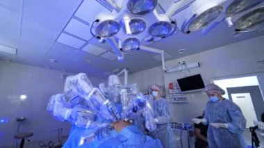 Modern ameliyathanede gelecekten gelen bir ameliyat. Robot makine minimal invaziv ameliyat yapıyor. Doktorlar hastanede cerrahi robotun çalışmalarını inceliyorlar..