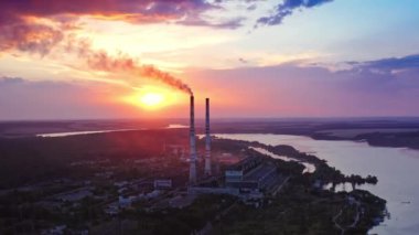 Gün batımında nehrin yanındaki fabrikada. Metalürji fabrikasından gelen tehlikeli duman havayı dolduruyor. Güzel mor arka planda kirli emisyonları olan endüstriyel fabrika.