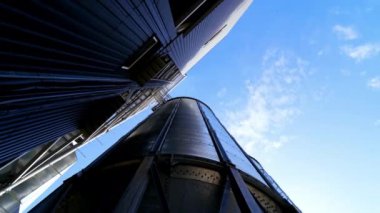 Depo tankları. Mavi gökyüzü arka planında tahıl asansörü. Tarım mahsulleri için büyük tahıl ambarı. Yakın plan. Hareket kamerası..