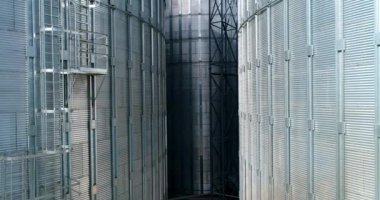Tahıl depolamak için büyük metal silo. Modern endüstriyel fabrika. Tahıl ambarı Tarım mahsulleri depolanan gümüş kaplar. Doğa arka planında tahıl asansörleri. Yakın plan. Yükselt.