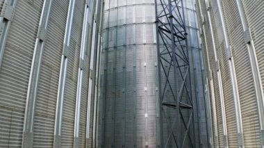 Modern bitkinin dışı. Dışarıda büyük metal tahıl asansörleri var. Ekin depolama ve işleme için alüminyum kaplar. Yakın çekim. Kamera yükseliyor..