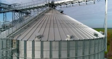 Modern tarım fabrikası. Doğa arka planında büyük tahıl terminalleri. Gümüş tahıl asansörleri. Hava görüntüsü. Kamera hareket ediyor.