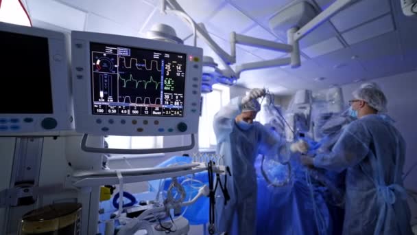 ロボット手術の背景の心拍数モニター 病院の医療バイタルサインモニター 新しい医療技術を用いた手術を行う医師団 — ストック動画