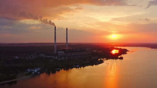 川の近くにある化学プラントのシルエット 工場は美しい日没時に煙を放出する 自然の中での危険な製造 エアリアルビュー — ストック動画