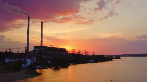 日没のピンクの空に対する有害な工場 産業煙突からの煙は環境を汚染する 夕方の川付近の化学プラント — ストック動画
