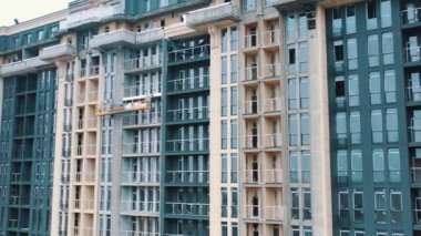 Şehirde modern bir bina inşa ediliyor. Şehirde plastik pencereleri olan çok katlı bir apartman dairesi. Yeni bir mimari inşaatı.