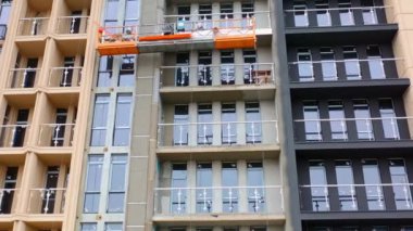 Yeni bir modern binanın ön görüntüsü. Yüksek katlı bir apartmanın inşaatı. İşçiler çok katlı bir binanın dış görüntüsünü oluşturuyorlar.
