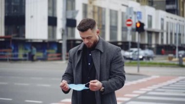 Genç adam koruyucu maske takıyor. Şehirde salgın sırasında güvenlik maskesi takan bir gencin portresi. Virüs koruması. Covid-19. Salgın Koronavirüs.