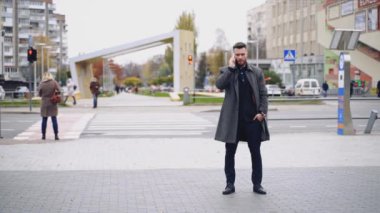 Dışarıda telefonla konuşan bir adamın portresi. Takım elbiseli ve ceketli yakışıklı bir işadamı caddede cep telefonu kullanıyor. Yavaş çekim.