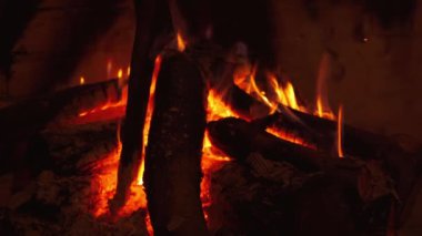 Şöminede yanan odunlar sıcak bir alev. Sıcak, karanlık bir arka plan, şöminede hafif ateş ve evde kütükler. Yakın plan..