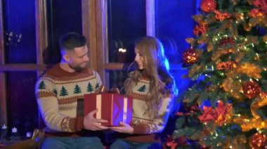 Erkek kadına Noel hediyesi veriyor. Mutlu güzel kız hediyesiyle birlikte bir kutu alır. Noel ağacının yanında birbirine aşık bir çift. Evde yeni yıl atmosferi.