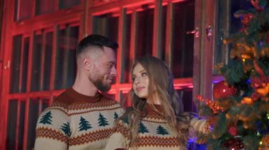 Birbirine aşık genç bir çift Noel toplarını asar. Evlerinde Noel ağacı süveteri ören mutlu bir çift. Noel ağacı süslemesi.