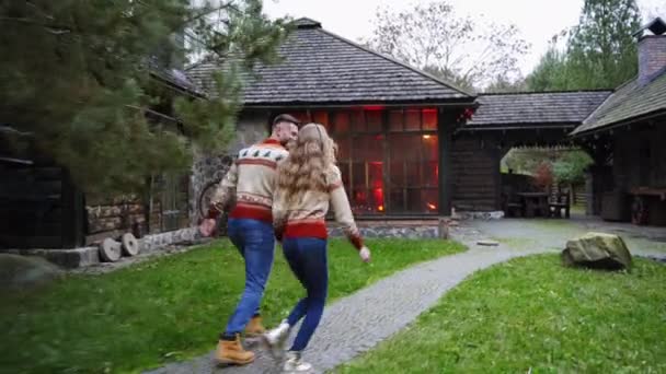 アウトドアで素敵なカップル テラスから家まで一緒に走る幸せな若者と女性 散歩後に暖かいコテージに入ってくる若い家族 — ストック動画